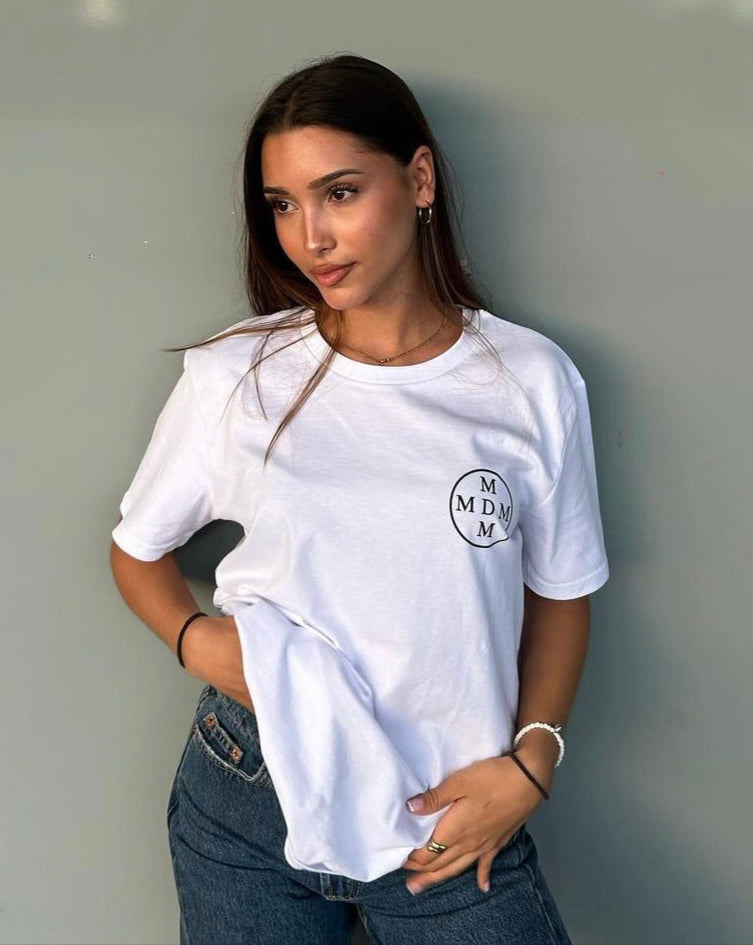 Woman wearing a white t-shirt with an mdm logo against a plain background